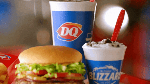 a dq drink and a blizzard are on a table with a hamburger