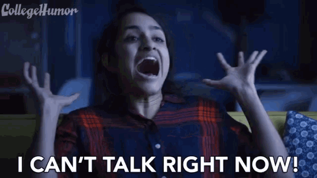 a woman is sitting on a couch with her mouth open and screaming while watching a movie .