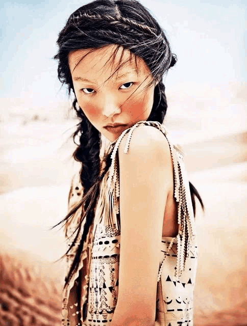 a woman with braids in her hair is wearing a fringed top