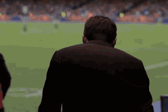 a man in a suit watches a soccer game