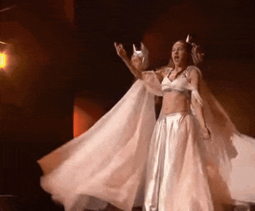 a woman in a long white dress is dancing on stage