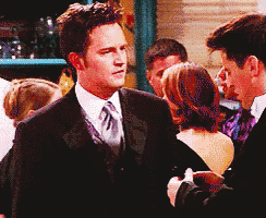 a man in a suit and tie shakes hands with another man in a tuxedo
