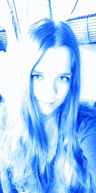 a woman with long blue hair looks at the camera