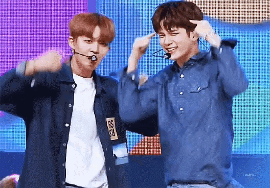 a couple of young men are standing next to each other on a stage and making funny faces .
