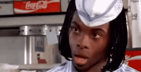 a young man wearing a white hat is making a funny face in a diner .