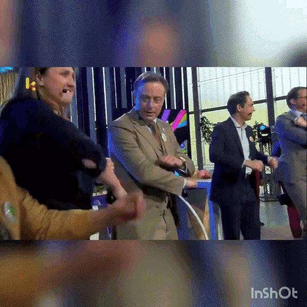 a man in a suit and tie is dancing in front of a group of people with the watermark inshot
