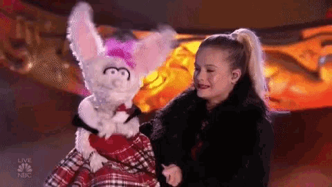 a young girl is holding a stuffed animal on stage .