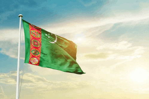 a green and red flag with a crescent moon is flying in the wind