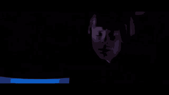 a close up of a person 's face in a dark room with a blue light behind them .