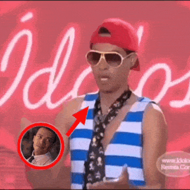 a man wearing sunglasses and a red hat is standing in front of a sign that says " idioos "