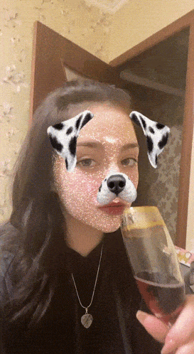 a girl with a dalmatian mask on her face is drinking from a glass