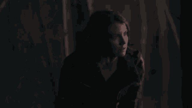a woman is standing in the dark looking at the camera .