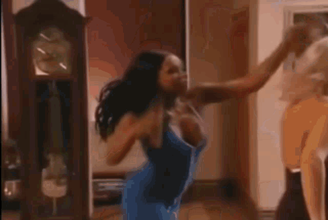 a woman in a blue dress is standing in a room with other women .