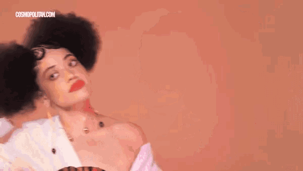 a woman with a large afro is holding her hair in a bun .