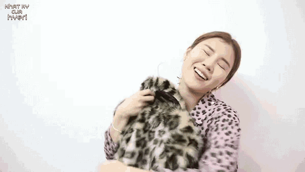 a woman wearing a leopard print fur coat is smiling with a red heart above her head
