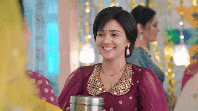 a woman in a purple dress is smiling while holding a metal container
