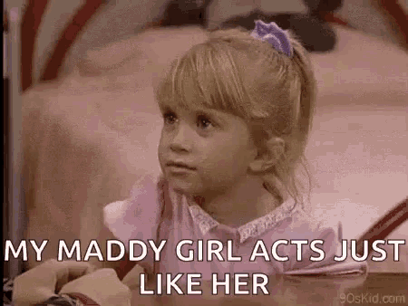 a little girl is sitting on a bed with the words `` my maddy girl acts just like her '' written on her face .