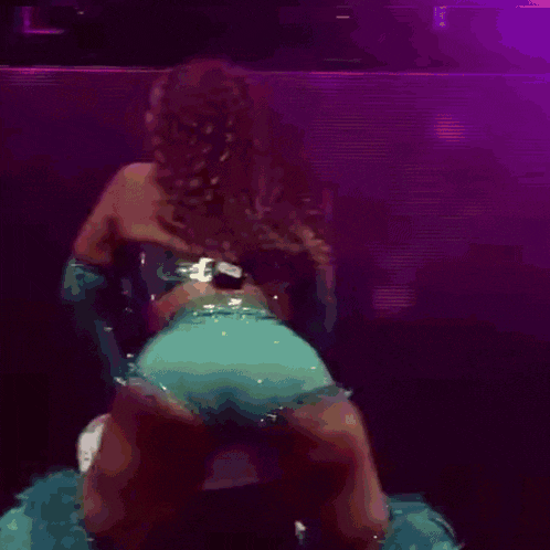 a woman in a blue dress is dancing on a stage with a pink background