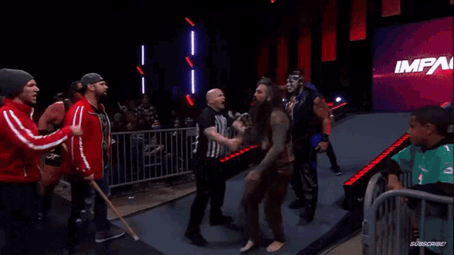 a referee is standing in front of a wrestling ring with the word impact on it