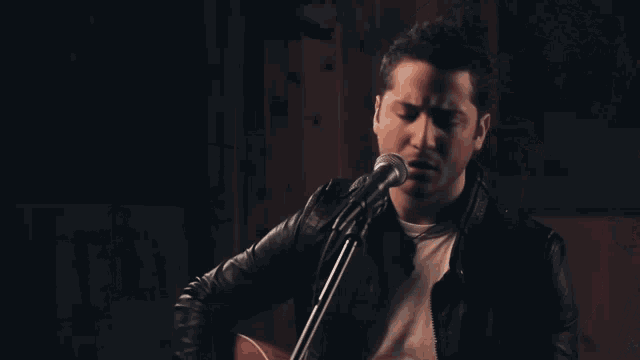 a man singing into a microphone with a dark background
