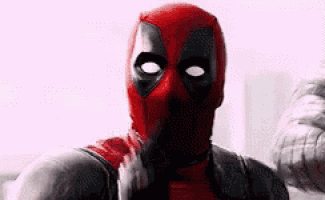 a close up of deadpool wearing a red mask and a gray suit .