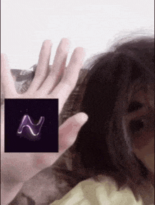 a person 's hand is reaching out towards a purple letter n on a black background