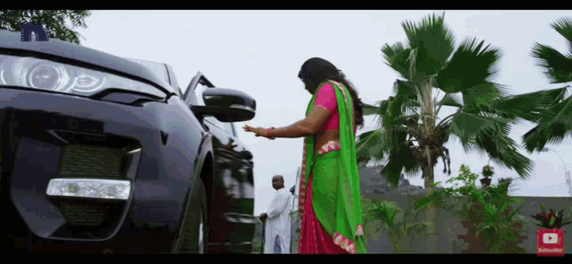 a woman in a green sari is standing next to a car