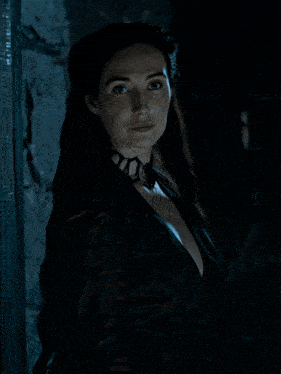 a man and a woman are standing next to each other in a dark room and the woman is smiling