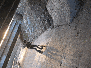a person is riding a scooter down a sidewalk under a bridge