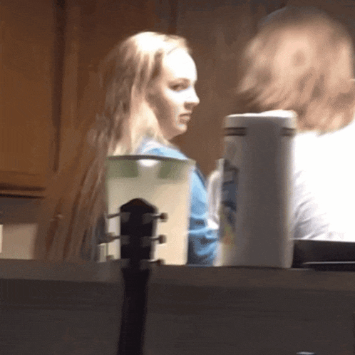 a woman is sitting at a table with a guitar and a pitcher