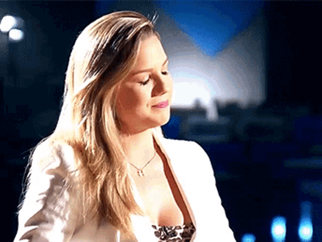 a woman wearing a white jacket and a necklace with a star on it