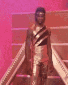 a man in a gold suit is walking down a set of stairs .