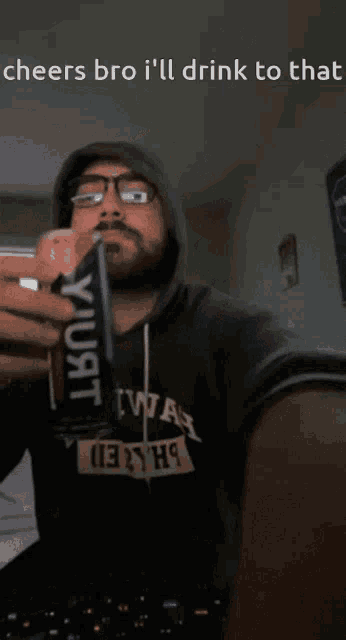 a man in a hoodie drinking from a can with the words cheers bro i 'll drink to that below him