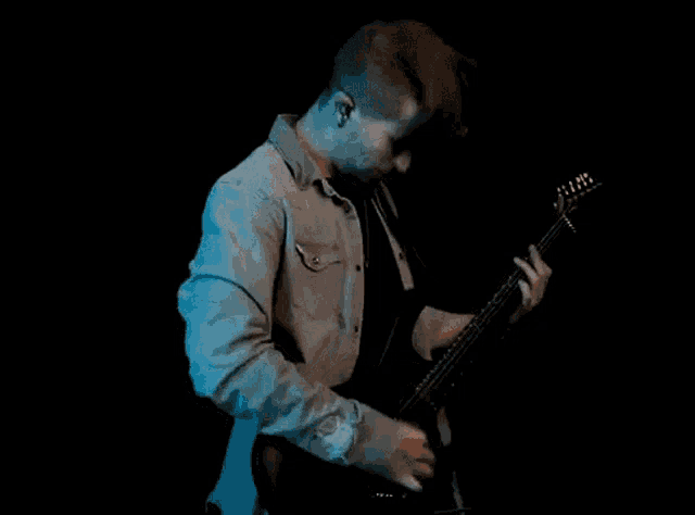 a man is playing a guitar and singing into a microphone .