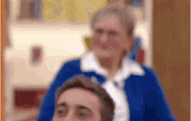 a blurry picture of a woman in a blue jacket standing next to a man 's head .