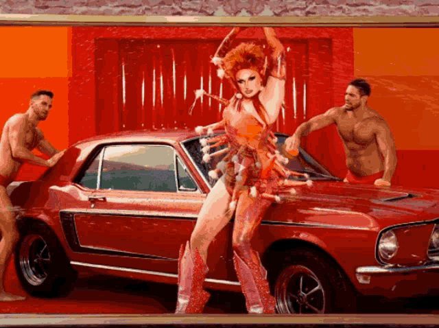 a drag queen is standing in front of a red mustang
