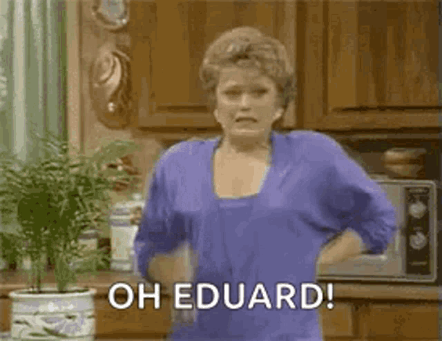 a woman is standing in a kitchen holding a bottle of water and saying oh eduard .