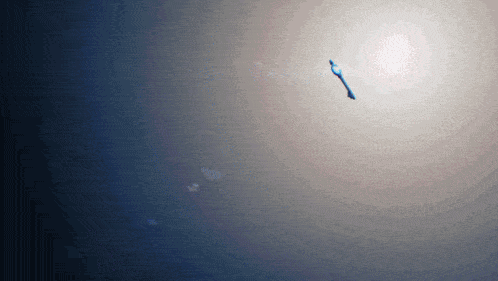 a blue object is flying through the air with the sun in the background