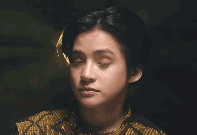 a close up of a person 's face with a black and gold shirt