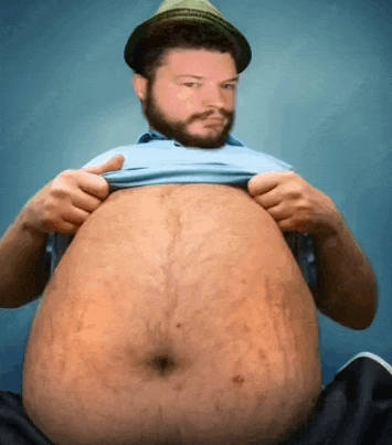 a man with a beard wearing a hat is holding his shirt over his stomach .