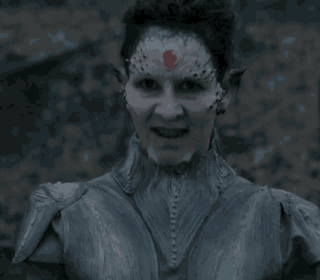 a woman with a red heart on her forehead is wearing a gray armored suit