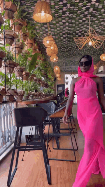 a woman in a pink dress and sunglasses is walking in a restaurant