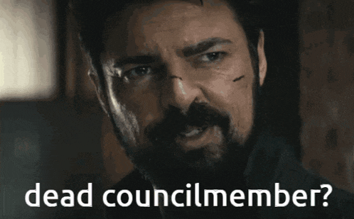 a man with a beard is smiling with the words dead councilmember below him