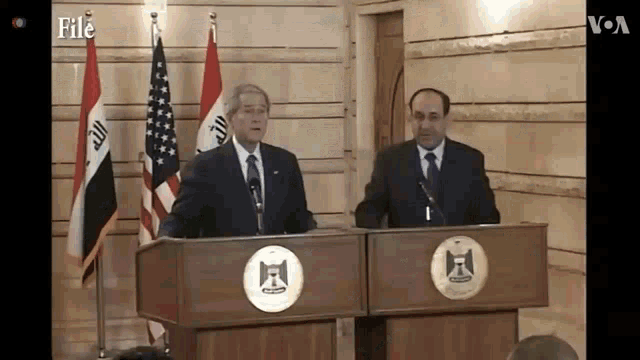 two men standing at podiums with flags in the background and the word file on the bottom right