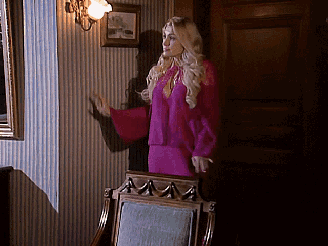a woman in a pink dress is standing in front of a mirror
