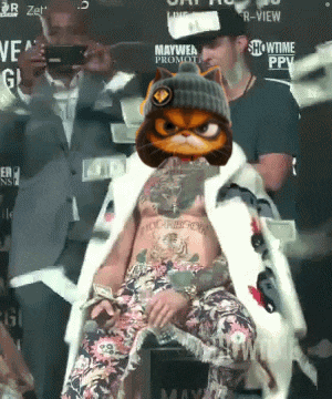 a man with a cat on his head is sitting in front of a showtime sign