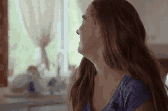 a woman with long hair is sitting in front of a window .