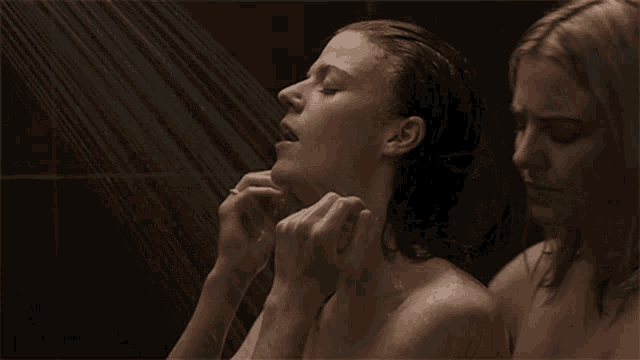 two naked women are taking a shower together and one of them has her eyes closed