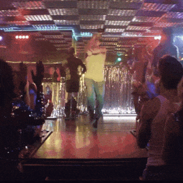a man in a white shirt is dancing in front of a crowd