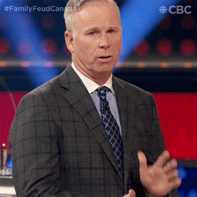 a man in a suit and tie is giving a speech on a stage with a cbc logo in the background